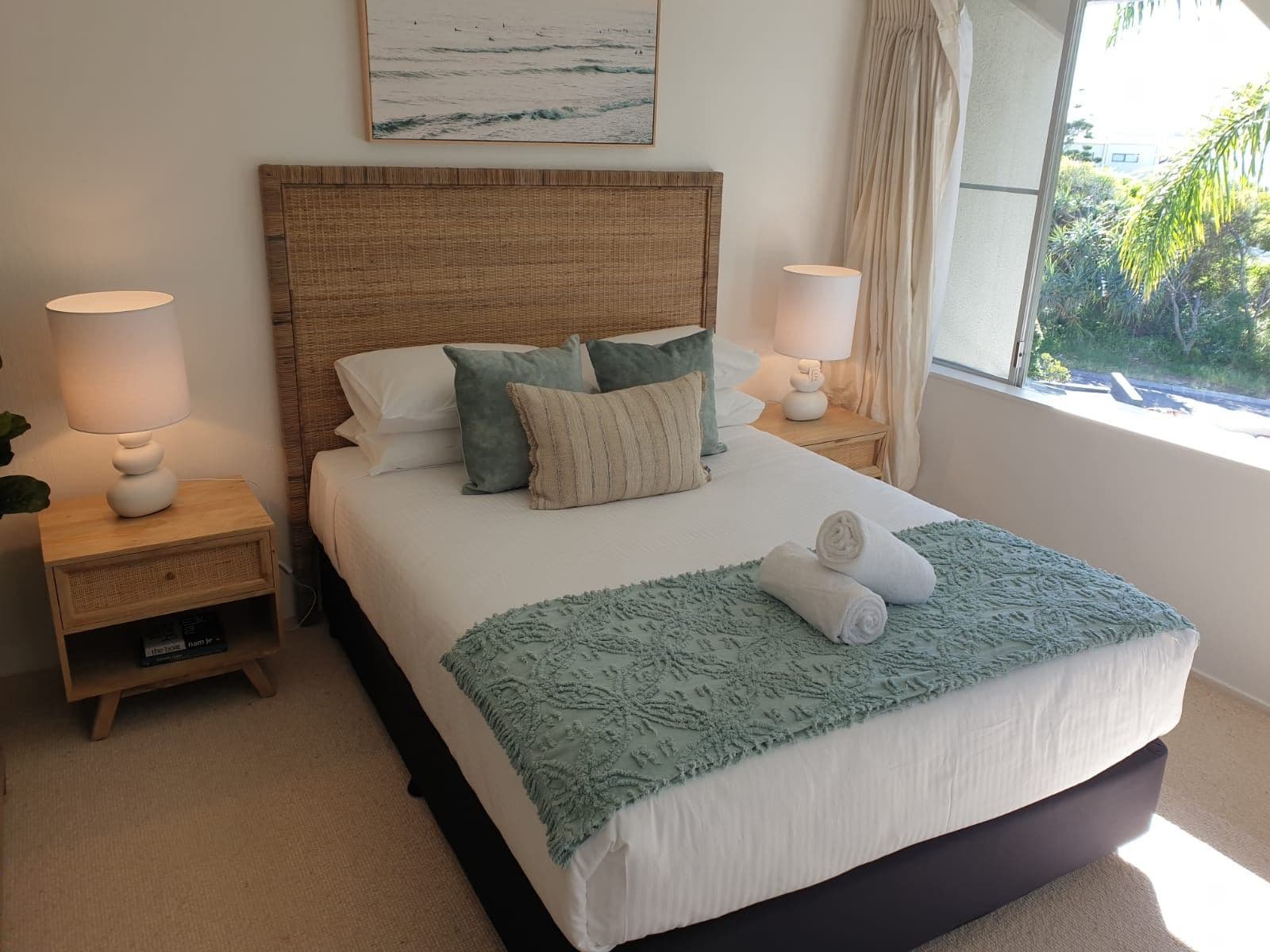 A guest-ready bedroom: bed made with fresh white linen and towels rolled neatly on the throw